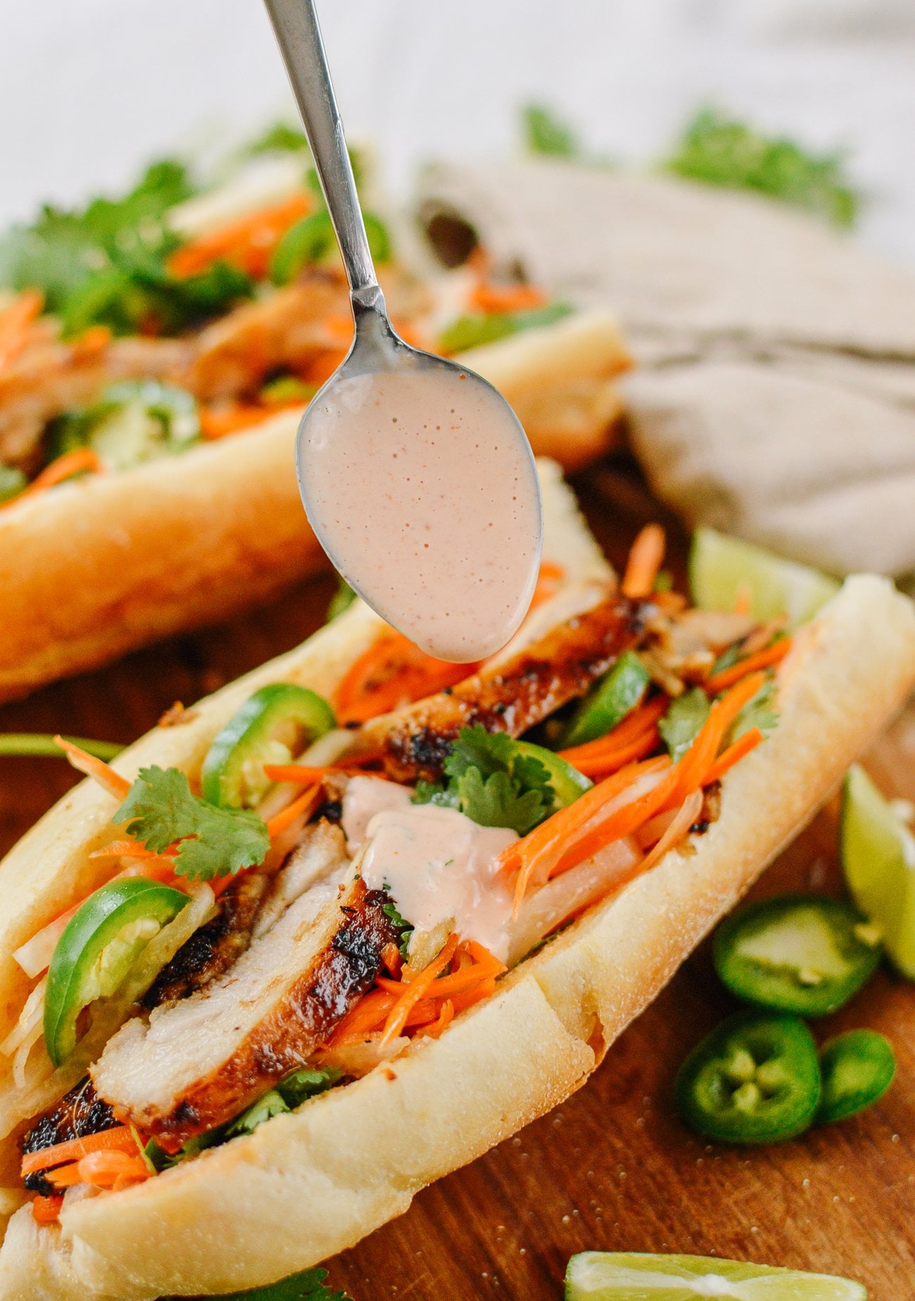 Pouring Sriracha mayo on lemongrass chicken banh mi