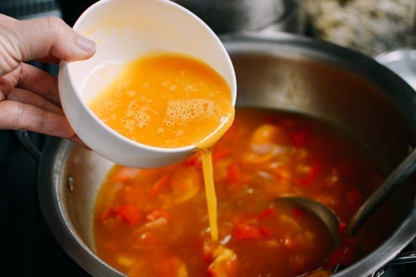 Adding egg to tomato egg drop soup, thewoksoflife.com