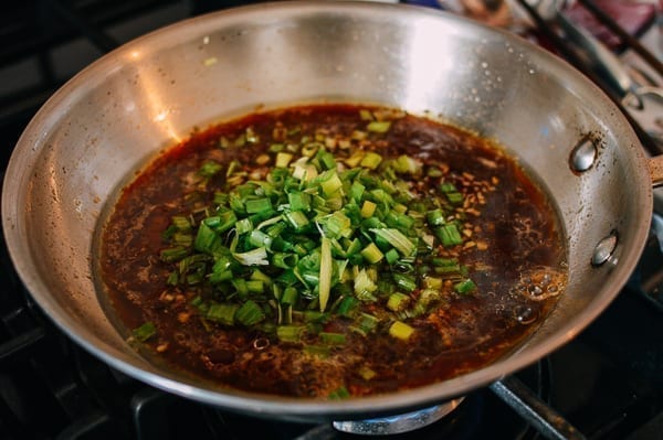 Adding scallions to sauce, thewoksoflife.com