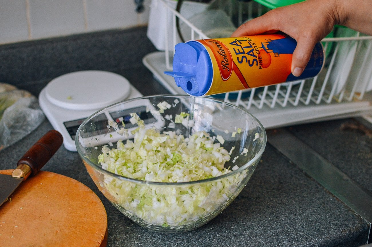 Adding salt to chopped napa cabbage in bowl