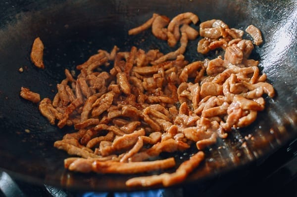 Browning pork strips in wok, thewoksoflife.com