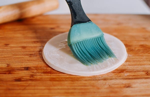 Brushing layers of dumpling wrappers with oil, thewoksoflife.com