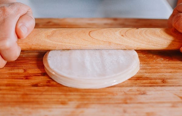 Pressing stack of dumpling wrappers with rolling pin, thewoksoflife.com