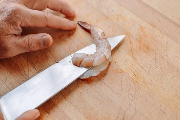 Slicing lengthwise through a peeled shrimp