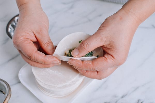 Pinching dumpling wrapper together at bottom corner, thewoksoflife.com