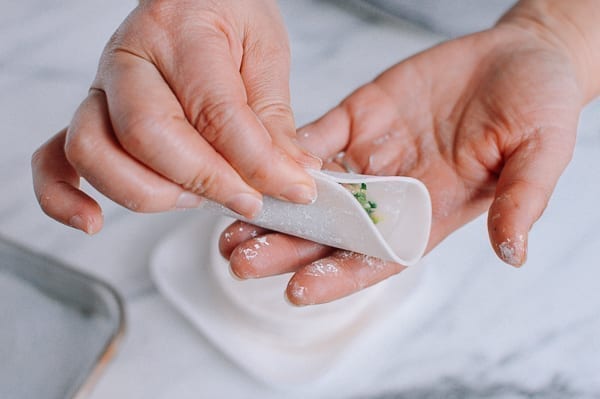 Folding dumpling wrapper in half, thewoksoflife.com