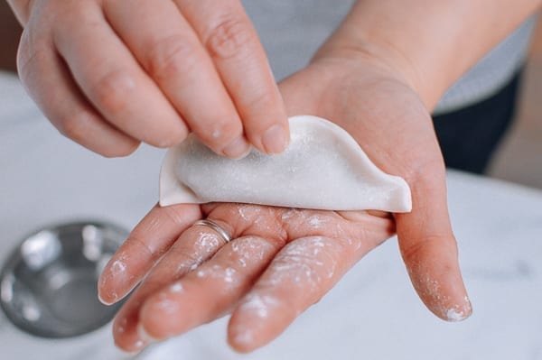 Flattening dumpling on palm of hand, thewoksoflife.com