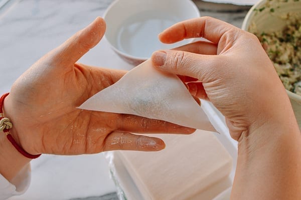 Folding wonton wrapper in half into a triangle, thewoksoflife.com