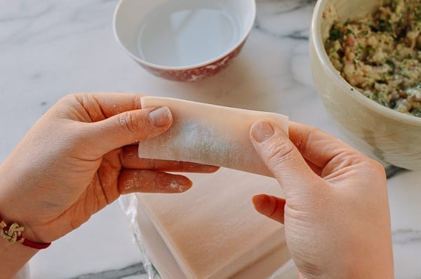 Folding wonton wrapper in half around filling, thewoksoflife.com