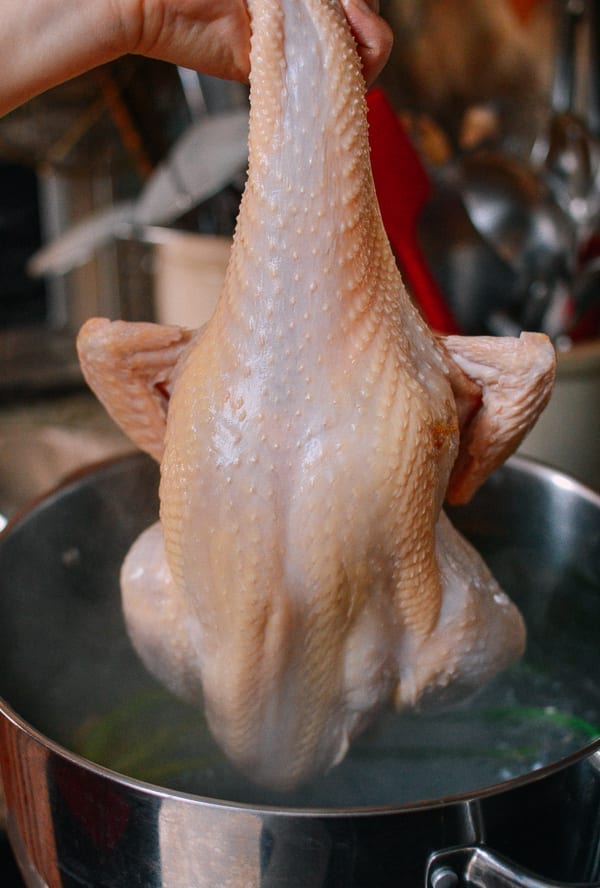 Lowering chicken into the pot, thewoksoflife.com