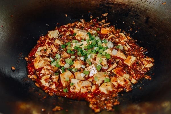 Adding scallions to mapo tofu, thewoksoflife.com