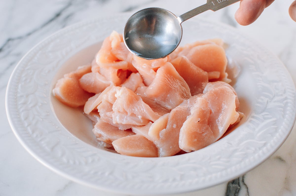 Adding water to sliced chicken, thewoksoflife.com
