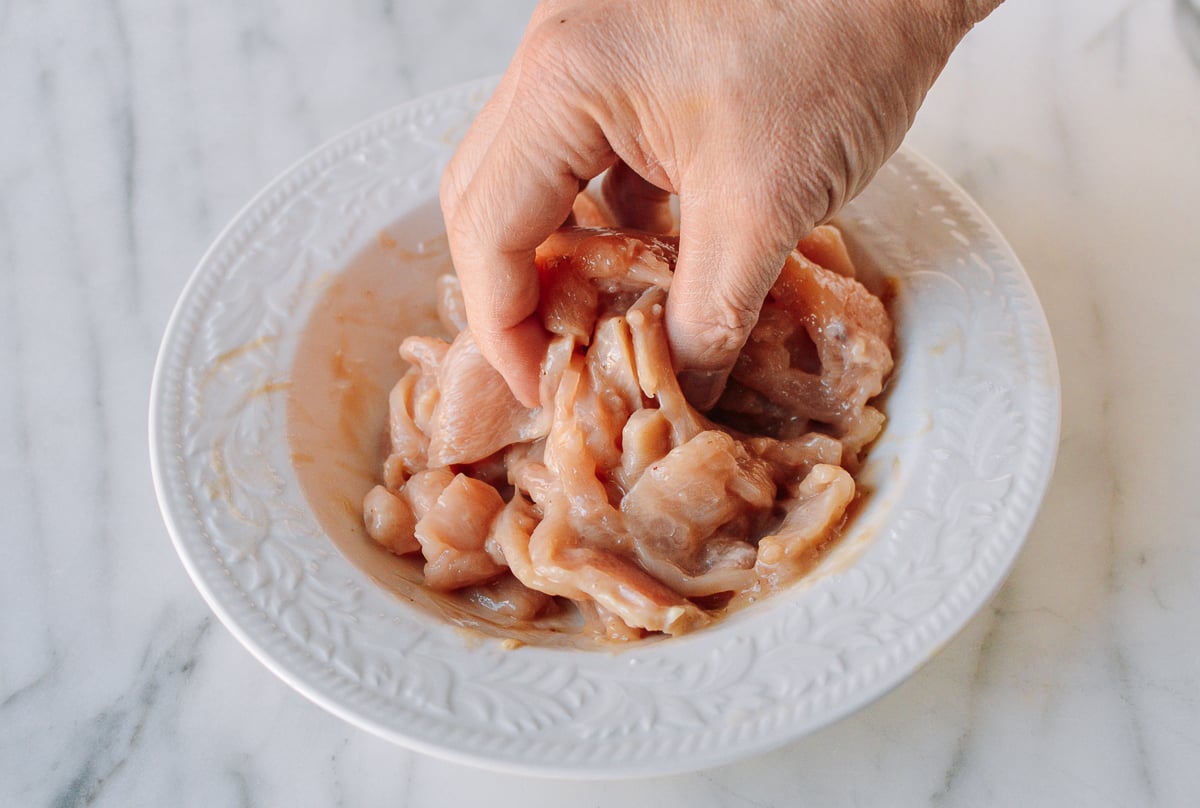 Mixing sliced chicken with marinade ingredients, thewoksoflife.com