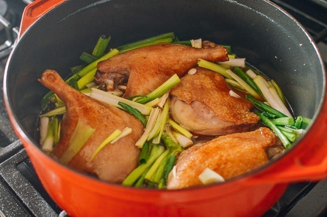 Duck legs in pot with aromatics and braising liquid, thewoksoflife.com