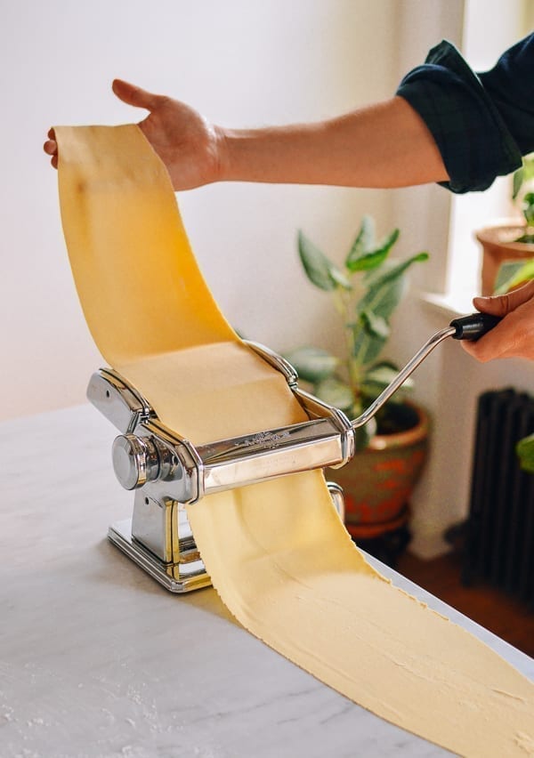 Rolling dough through thin setting of pasta roller, thewoksoflife.com