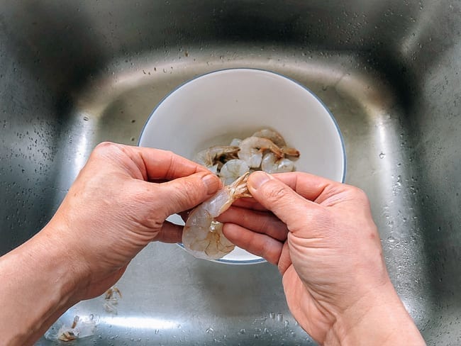 Peeling shell of shrimp tail meat, thewoksoflife.com