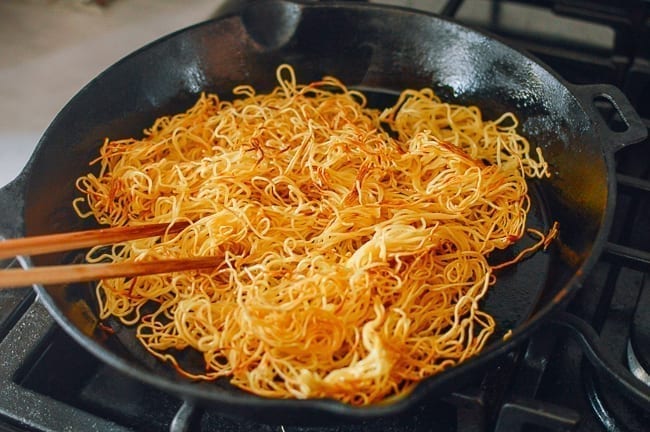 Breaking up fried noodles with chopsticks, thewoksoflife.com