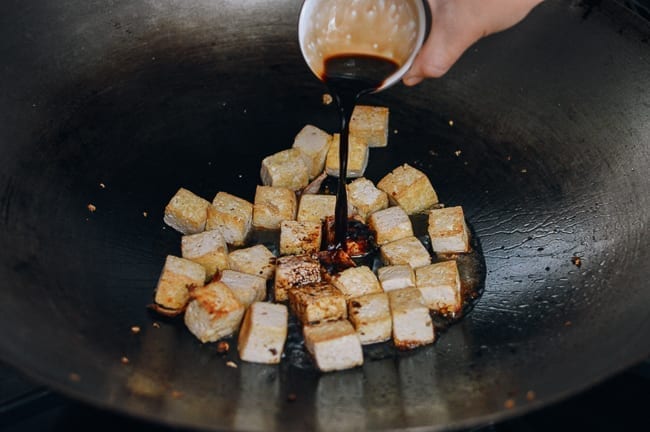 Adding light soy sauce to tofu, thewoksoflife.com