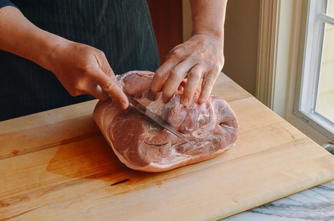 Cutting open pork picnic shoulder to reveal bone, thewoksoflife.com