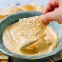 Dipping tortilla chip into plain vegan queso, thewoksoflife.com