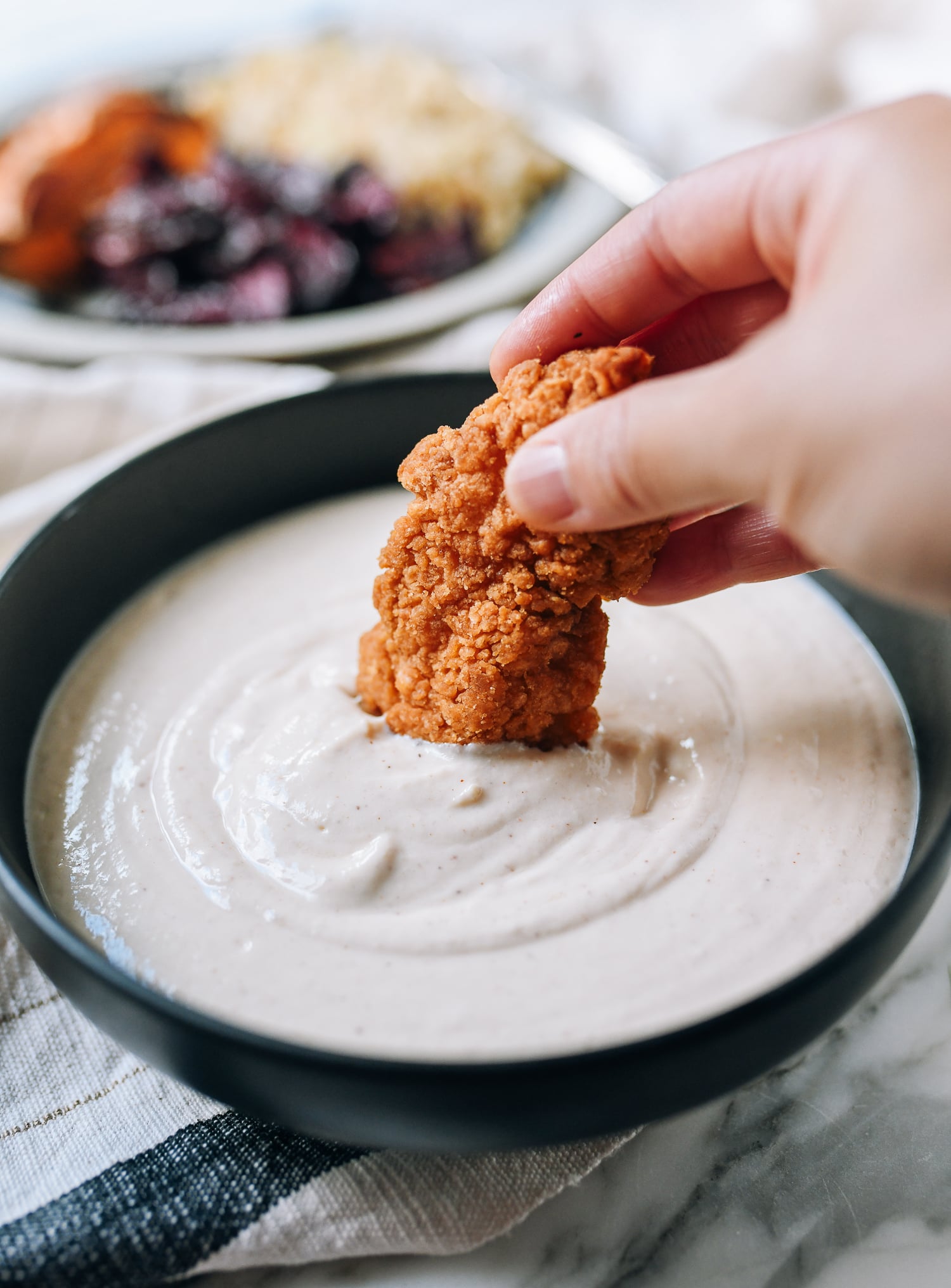 Dipping chicken finger into tofu garlic aioli, thewoksoflife.com