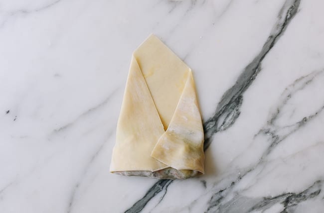 Folding both sides of egg roll wrapper into the middle, thewoksoflife.com