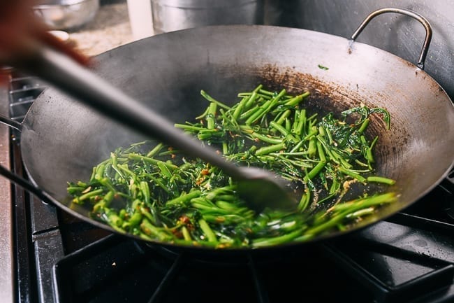 Stir-frying water spinach on hot sides of wok