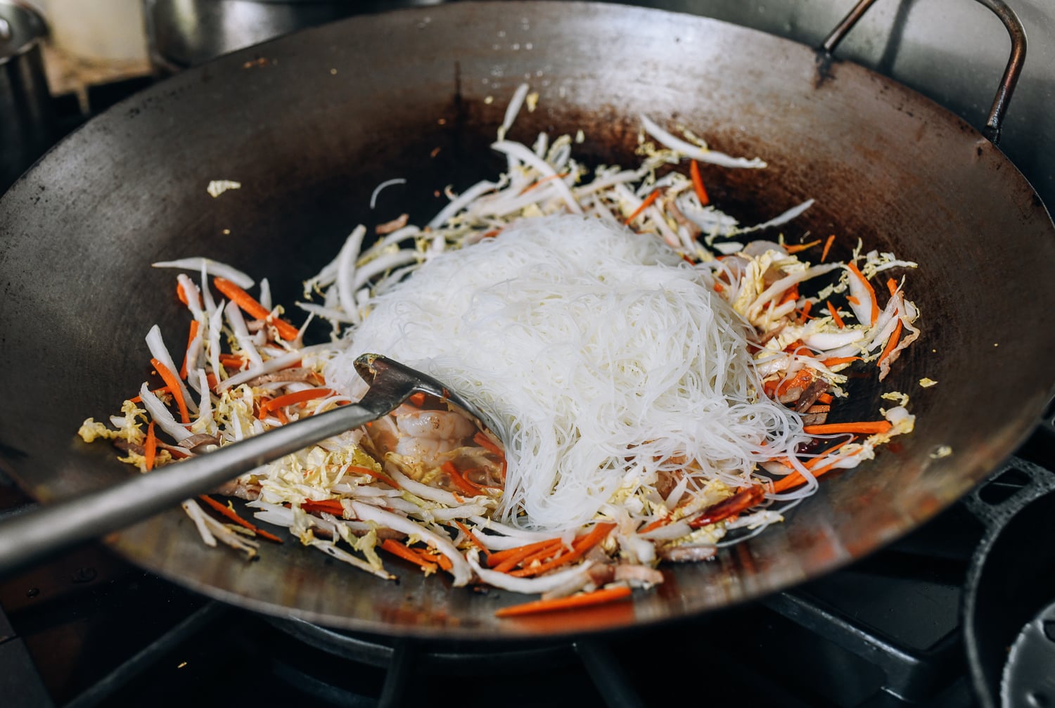 Adding the rice noodles to the wok, thewoksoflife.com