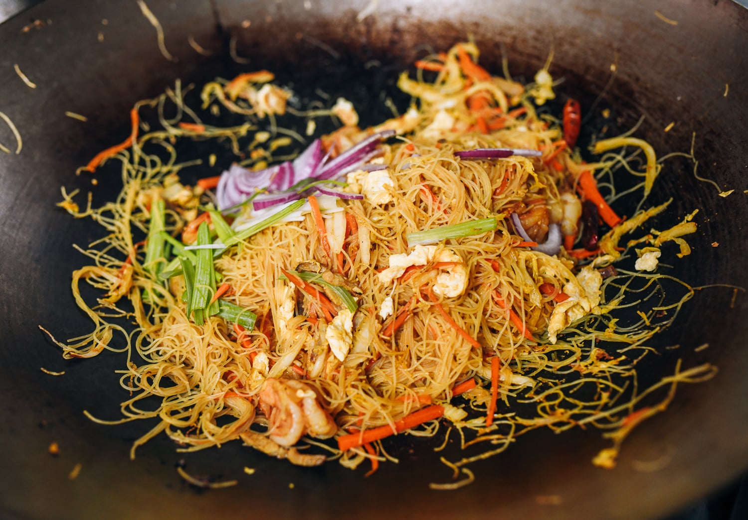 Adding scallions and red onion to Singapore Mei Fun, thewoksoflife.com