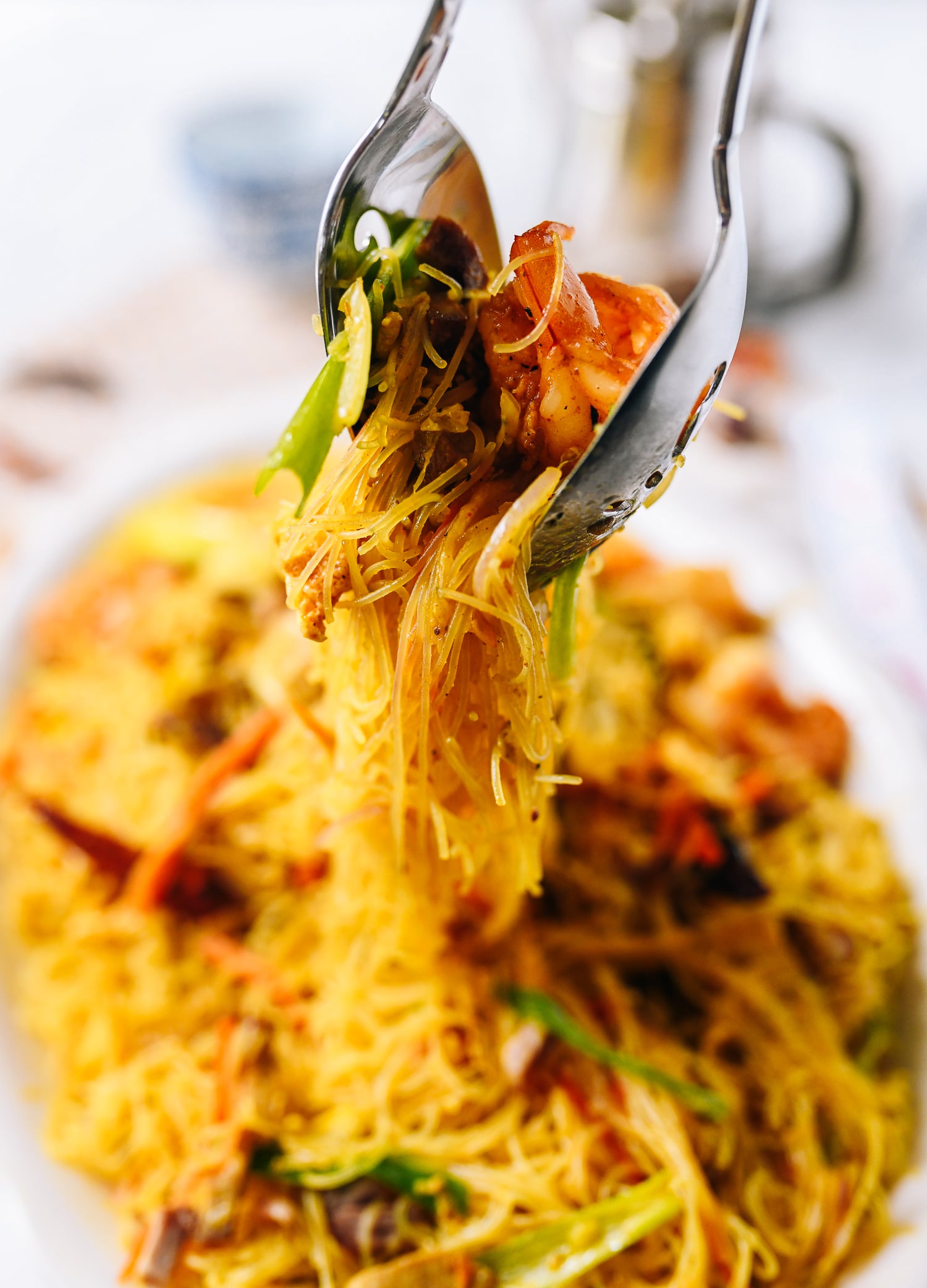Lifting Singapore noodles off plate with two spoons, thewoksoflife.com