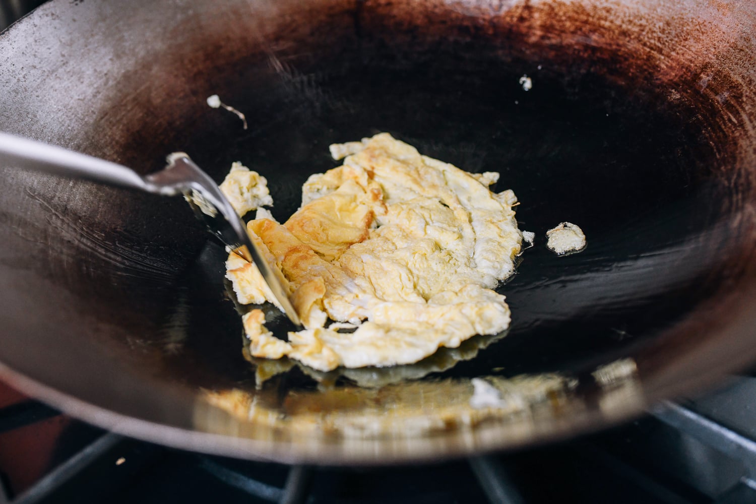 Breaking up scrambled eggs with wok spatula, thewoksoflife.com