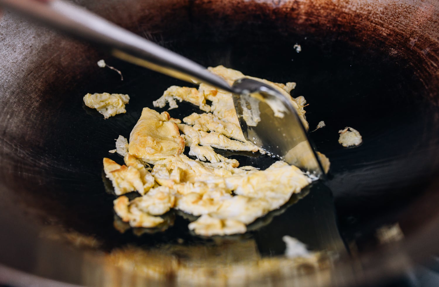 Breaking up scrambled eggs with wok spatula, thewoksoflife.com