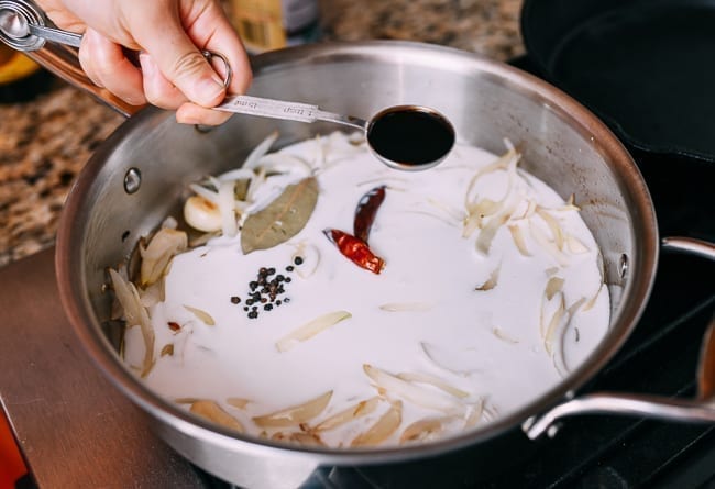Adding soy sauce and aromatics to Filipino adobo sauce, thewoksoflife.com