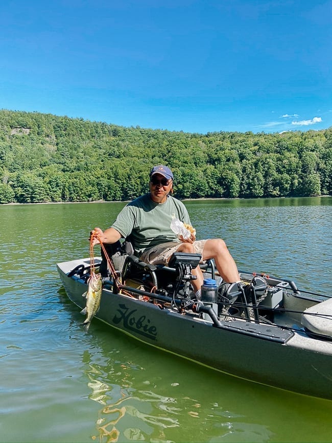 Bill on fishing kayak holding catch, thewoksoflife.com