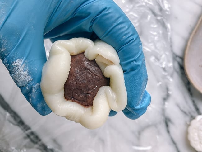 Wrapping mooncake dough around filling, thewoksoflife.com