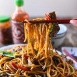 Picking up beef lo mein with chopsticks, thewoksoflife.com