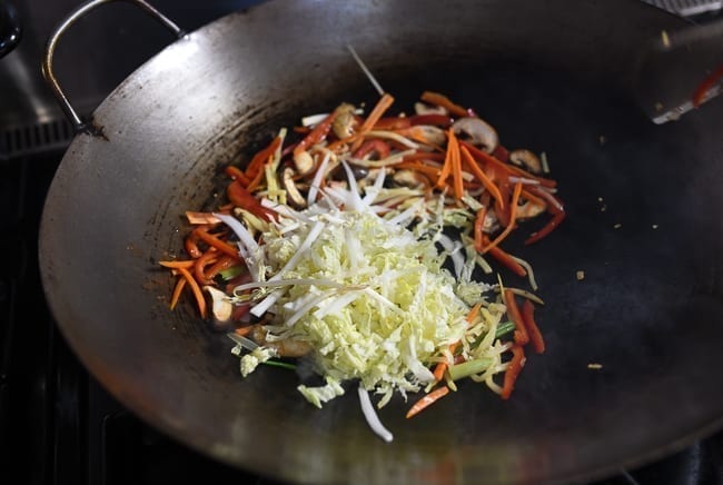 Adding napa cabbage to other vegetables in wok, thewoksoflife.com