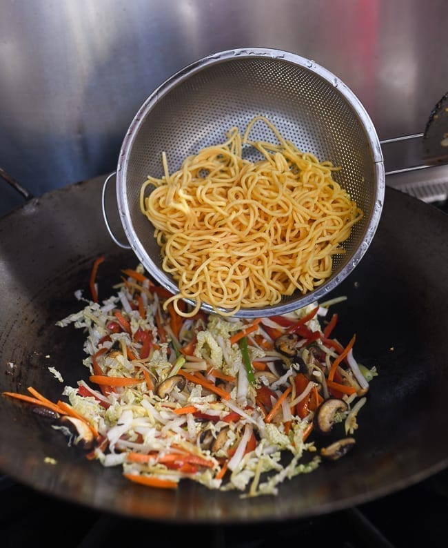 Adding lo mein noodles to vegetables in wok, thewoksoflife.com