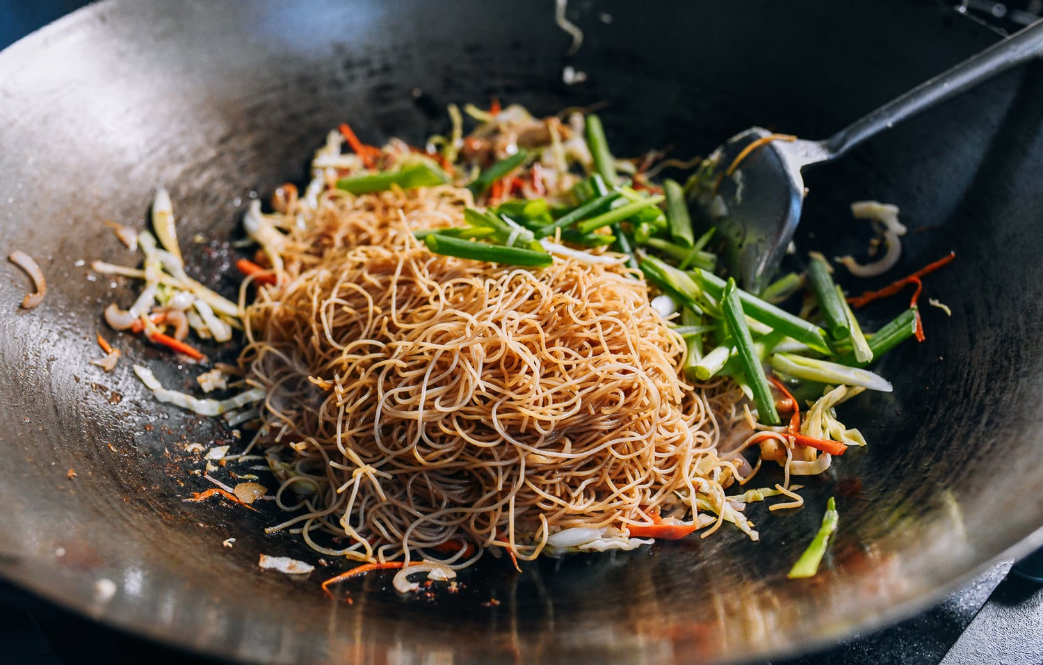 Adding rice noodles and scallions to wok, thewoksoflife.com