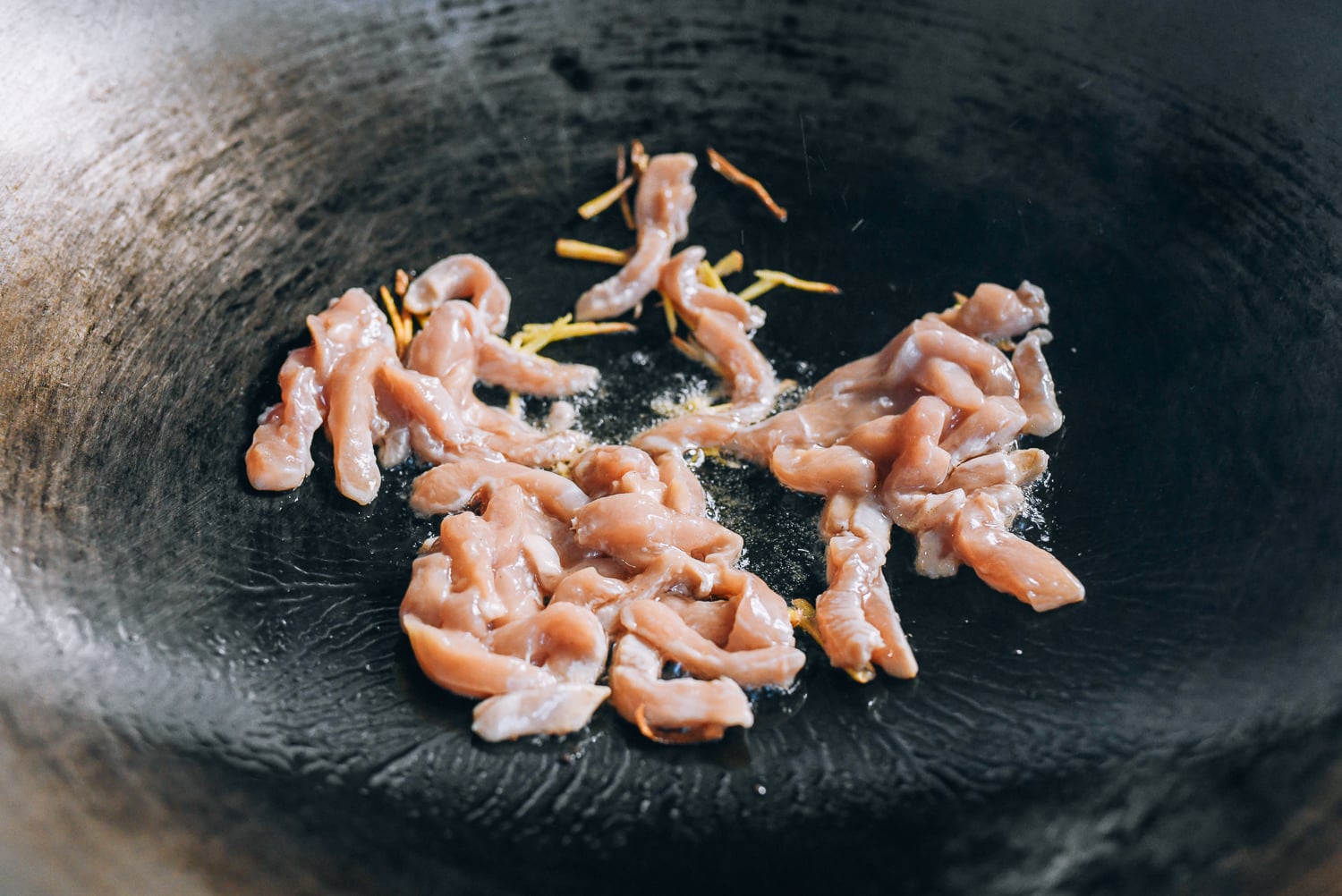 Adding chicken to ginger in wok, thewoksoflife.com