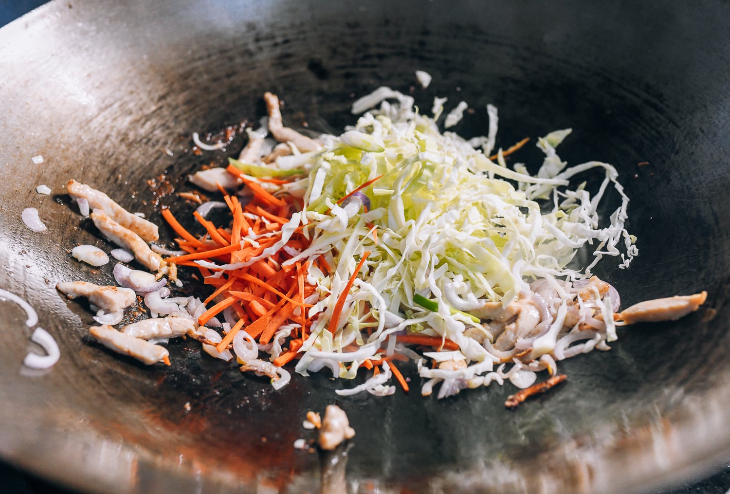 Adding cabbage and carrots to the stir-fry, thewoksoflife.com
