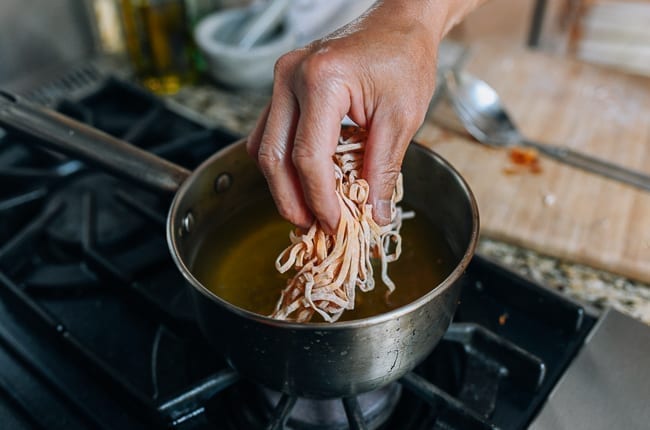 Dropping small handful of egg noodles into hot oil