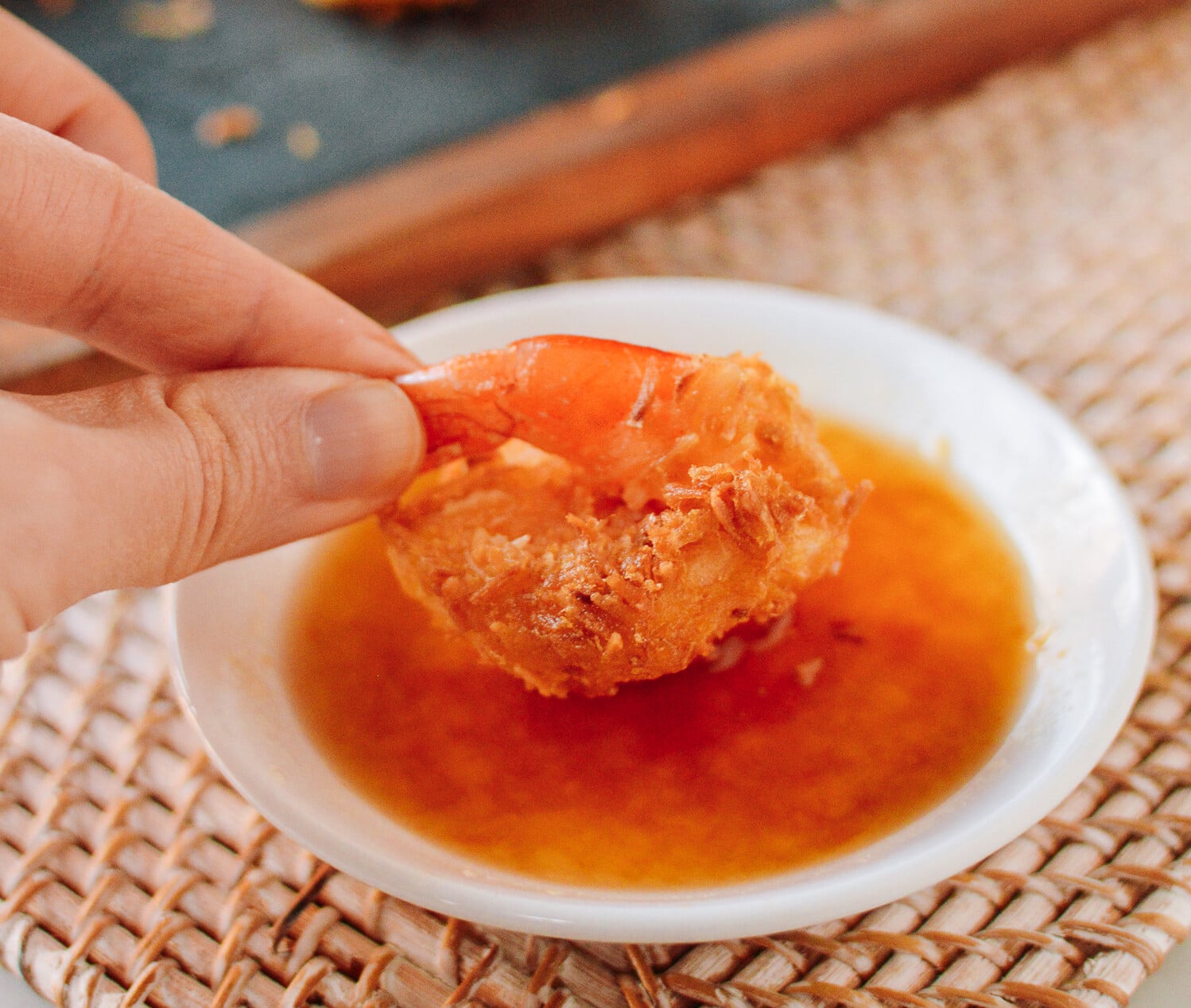 dipping coconut shrimp into sauce