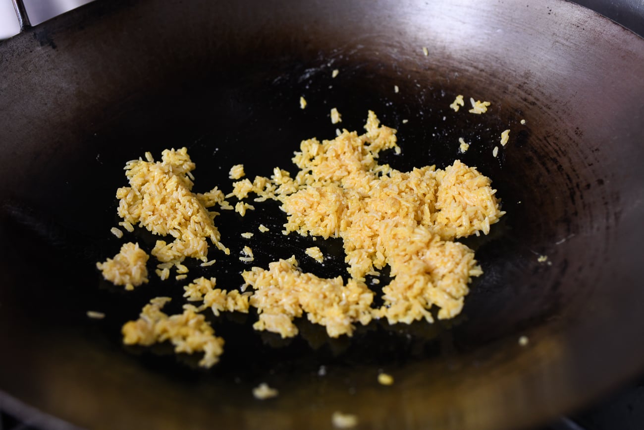 Stir-frying egg yolk coated rice in wok