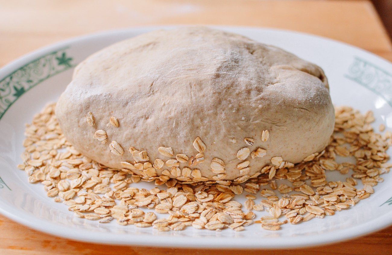 rolling loaf of bread dough in oats