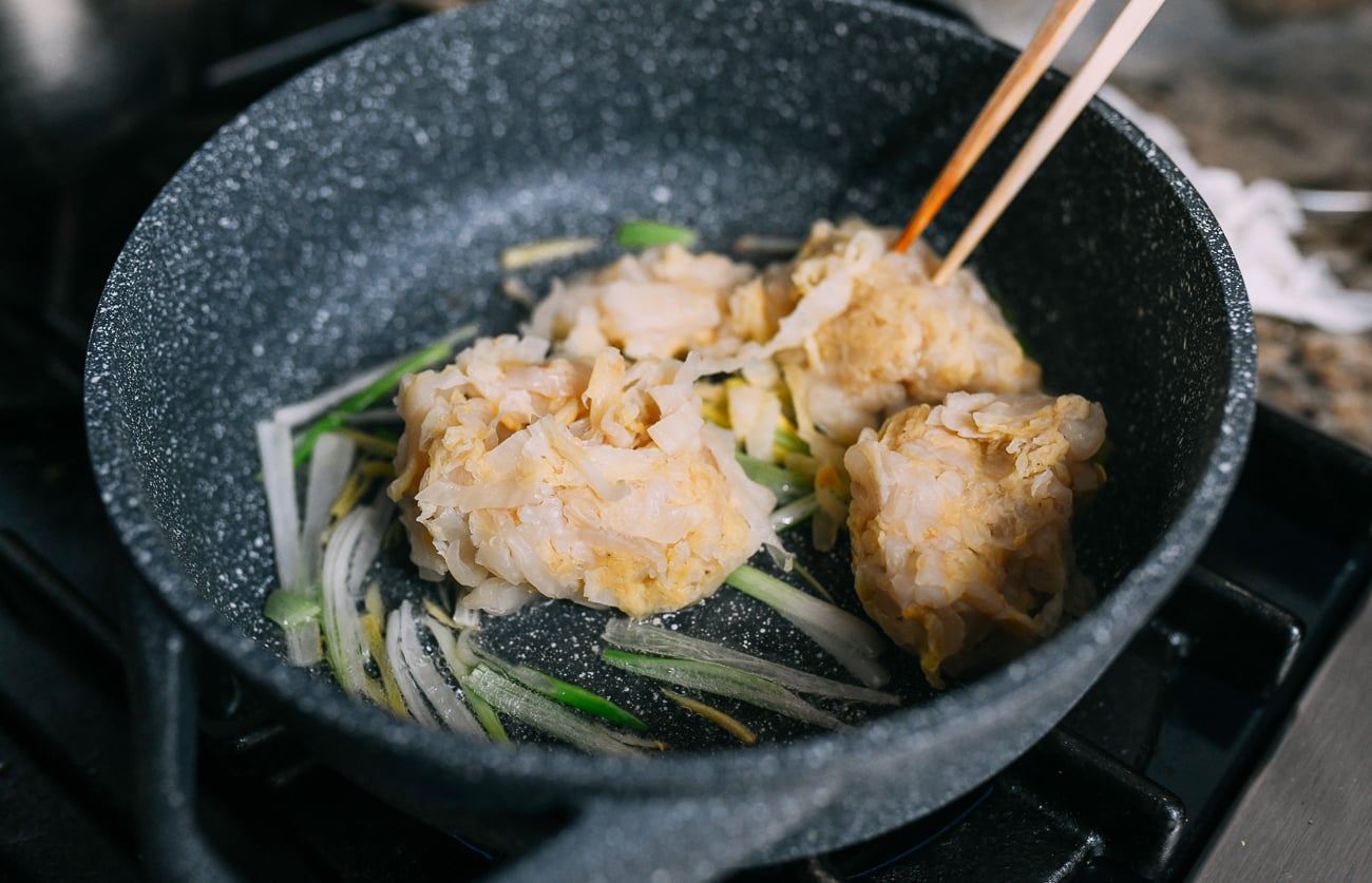 Adding sour cabbage to ginger and scallions