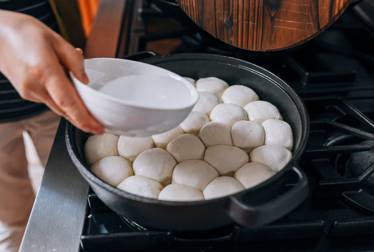 Adding water to pan of Shengjian Bao, thewoksoflife.com