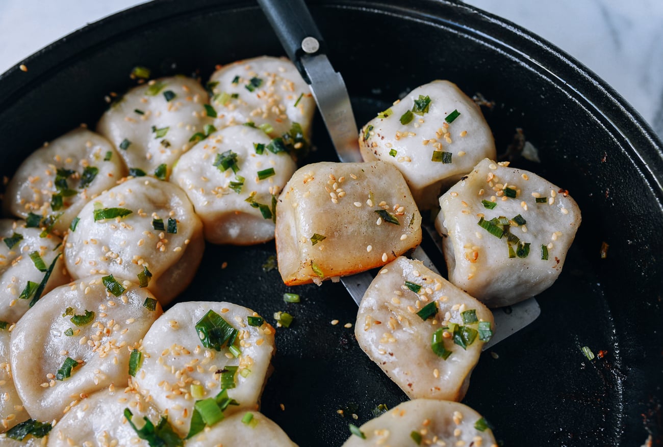Taking Shengjian Mantou out of cast iron pan with spatula, thewoksoflife.com