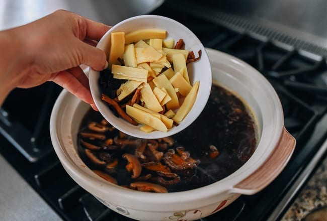 Adding mushrooms, lily flowers, and bamboo shoots to pot of soup, thewoksoflife.com