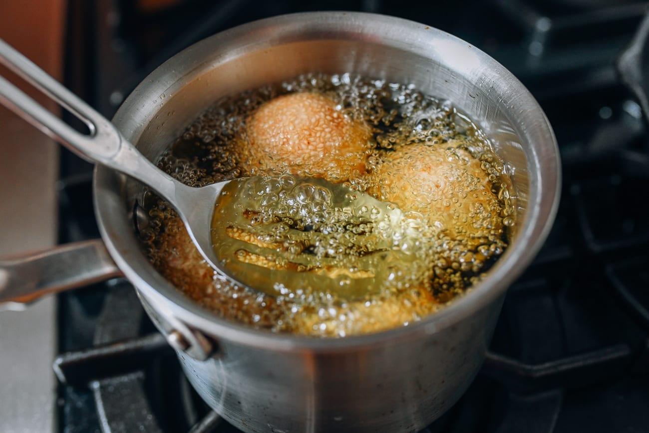 Submerging sesame balls in frying oil